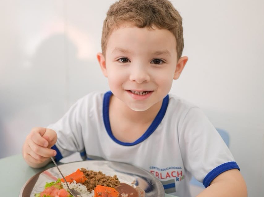 Aluno da Erlach Kids à mesa, com o prato do almoço servido pela escola