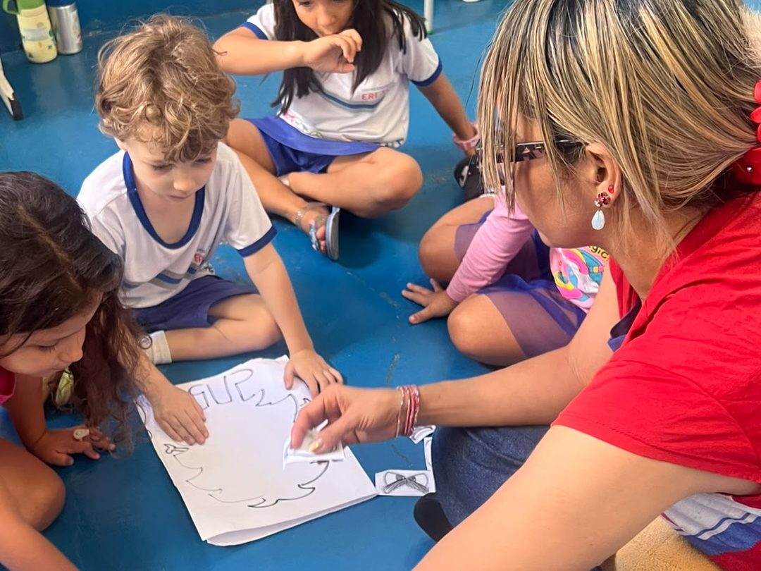 Professora e alunos da Erlach Kids em atividade de inglês no chão da área coberta