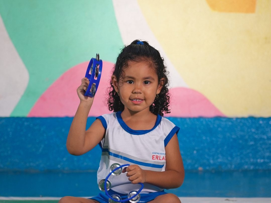 Aluna da Erlach Kids tocando pandeiro na aula de música